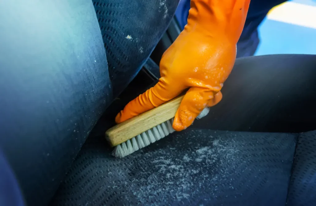 Person using a lint roller to remove dog hair from car seats.